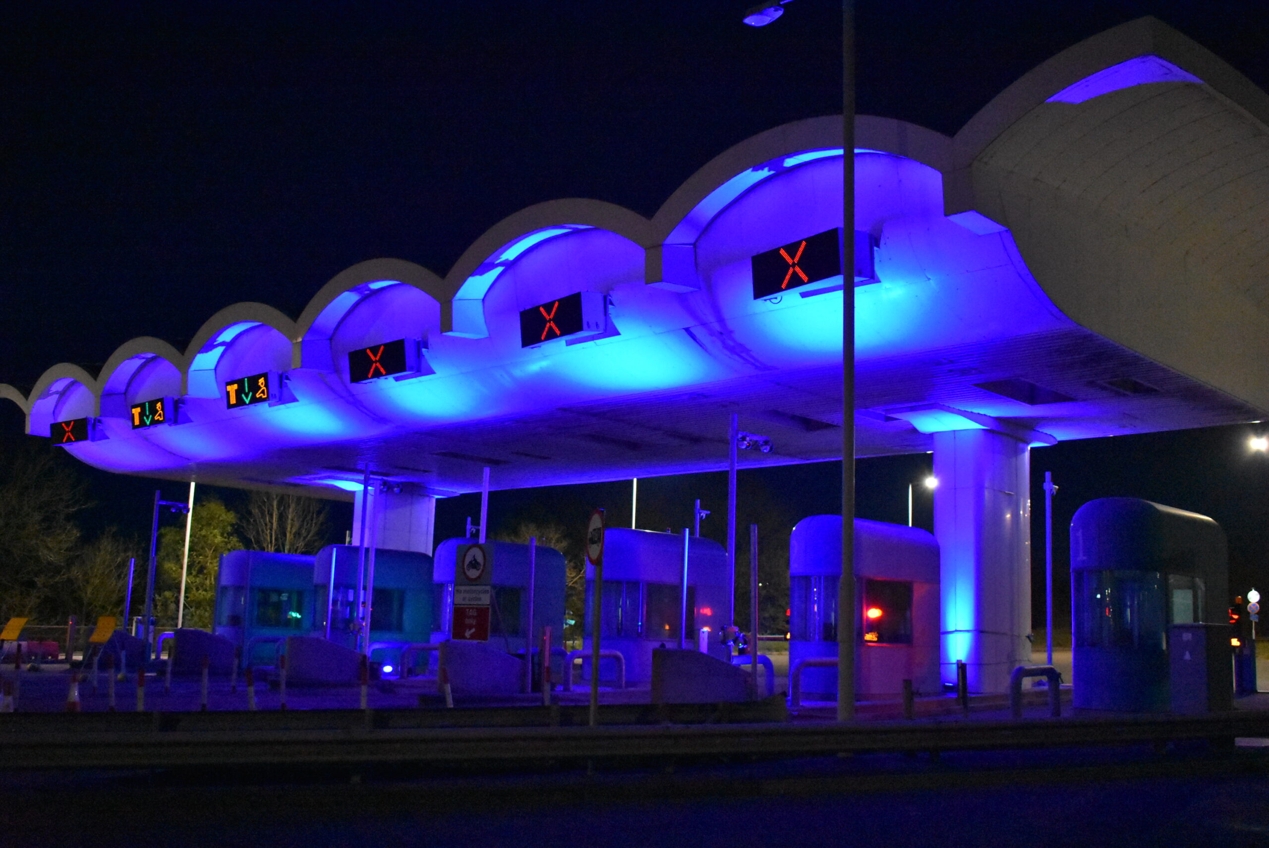 The Tamar Bridge tolls lit up in a blue light at night.